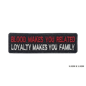 Może przedstawiać: Czarna prostokątna naszywka z haftem z napisem "BLOOD MAKES YOU RELATED" w kolorze czerwonym i "LOYALTY MAKES YOU FAMILY" w kolorze białym. Naszywka ma wymiary 9,5 cm x 3,5 cm.