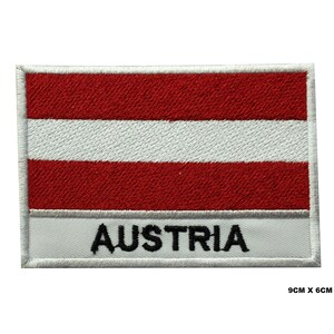 Könnte beinhalten: Gestickter Aufnäher mit der österreichischen Flagge mit roten und weißen Streifen und dem Wort "AUSTRIA" in schwarzen Buchstaben auf weißem Hintergrund. Der Aufnäher misst 9 cm x 6 cm.