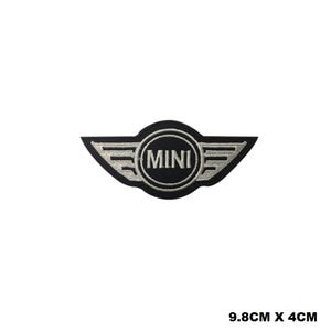 Puede incluir: Parche de planchado bordado en blanco y negro con el logotipo de Mini Cooper. El logotipo es un círculo con la palabra "MINI" en letras blancas y dos alas plateadas.