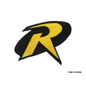 May include: An embroidered patch featuring a stylised yellow letter R set against a black oval background. The design has sharp, angular edges and measures 7cm x 8.5cm as indicated by the text printed in the bottom right corner of the image.