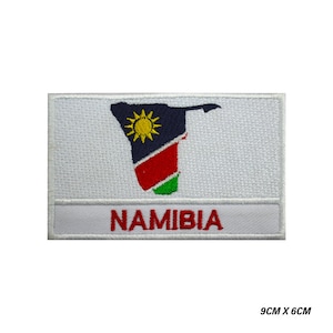 May include: White embroidered patch with the outline of Namibia in the colors of the Namibian flag. The text "NAMIBIA" is written in red below the outline. The patch measures 9 inches by 6 inches.