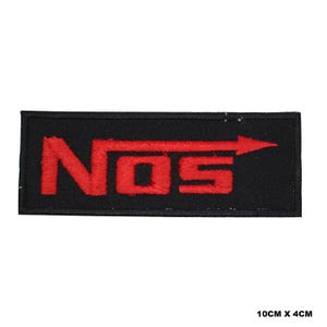 Puede incluir: Parche rectangular negro con el texto rojo bordado "NOS" y una flecha que apunta hacia la derecha. Mide 10 cm x 4 cm.