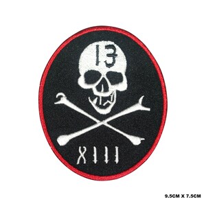 May include: Embroidered patch with a black background, a white skull, crossed wrenches, and the number 13. The patch has a red border and the text "8111" below the crossed wrenches. The patch measures 3.7 inches by 3 inches.
