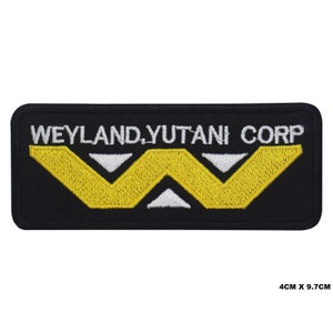 May include: Black embroidered patch with the text "Weyland-Yutani Corp" in white and a yellow stylized "W" logo.