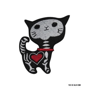 Op de afbeelding: Zwart-witte geborduurde strijkpatch van een skeletkat met een rood hart. De kat draagt een rode halsband. De patch is 10 x 8,8 cm.
