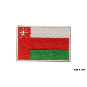 Pode incluir: Um remendo bordado da bandeira de Omã. A bandeira é branca com uma faixa vermelha e uma faixa verde na parte inferior. A bandeira tem um símbolo branco no canto superior esquerdo. O remendo mede 9 cm por 6 cm.