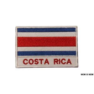 Peut inclure: Patch brodé représentant le drapeau du Costa Rica avec des bandes bleues, blanches et rouges. Le patch est blanc avec les mots "COSTA RICA" en rouge.