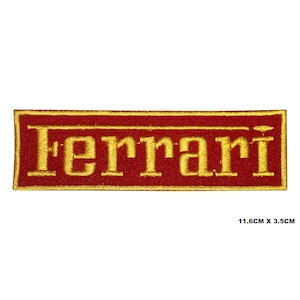 Könnte beinhalten: Ein roter und goldener gestickter Aufnäher mit dem Wort "Ferrari" in goldenen Buchstaben. Der Aufnäher ist 11,6 cm x 3,5 cm groß.