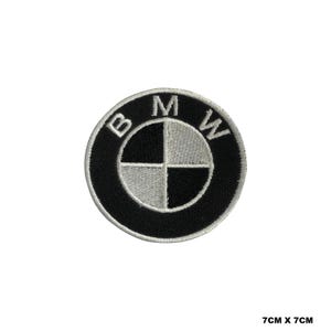 Può includere: Toppa ricamata in bianco e nero con il logo BMW. Il logo è un cerchio bianco con un design a elica nero all'interno. Le lettere "BMW" sono bianche e circondano il cerchio.