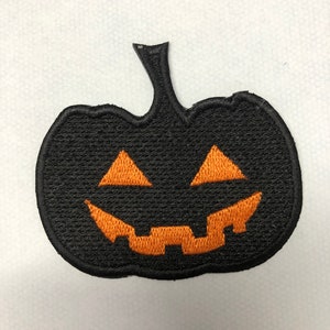 May include: Black felt pumpkin patch iron-on applique with an orange embroidered jack-o'-lantern face.