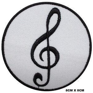 May include: A white circular patch with a black treble clef embroidered on it. The patch measures 8 cm by 8 cm.
