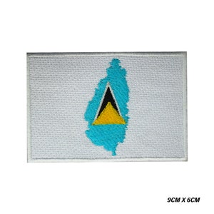 Pode incluir: Etiqueta bordada da bandeira de Santa Lúcia. A bandeira é azul com um triângulo amarelo e um triângulo preto dentro. A etiqueta mede 9 cm por 6 cm.