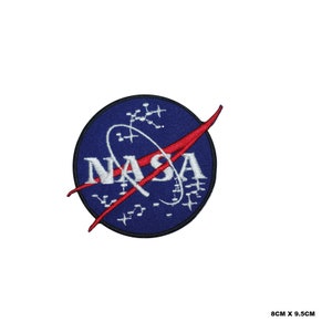 Puede incluir: Un parche bordado de la NASA azul y rojo con un círculo blanco y la palabra "NASA" en letras blancas. El círculo tiene un diseño blanco de un planeta y estrellas. El parche mide 8 cm por 9,5 cm.