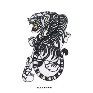 May include: White embroidered iron-on patch of a black and white tiger with a yellow mouth. The tiger is facing left and has its tail curled around its body. The patch is 10.5 x 6.5 cm.