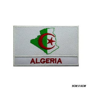 May include: White embroidered patch with the outline of Algeria in green and a red crescent moon and star inside. The word "ALGERIA" is written in red below the outline.