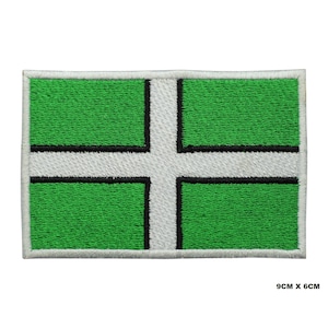 May include: Embroidered patch featuring the flag of Devon, England. The rectangular patch has a green background with a white cross and a black border. The patch measures 9cm x 6cm.