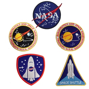 May include: Five embroidered patches featuring NASA logos. The patches are blue, red, yellow, and white. One patch features the text "SPACE SHUTTLE".
