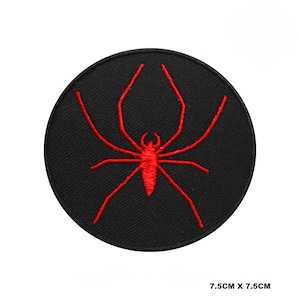 以下が含まれることがあります： 黒い円形のワッペンに赤い刺繍のクモが描かれています。ワッペンは直径7.5cmです。