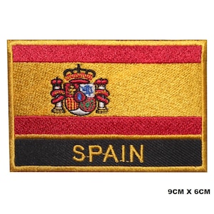 Puede incluir: Parche bordado con la bandera española con el escudo de armas y la palabra "ESPAÑA" en letras doradas sobre fondo negro. El parche mide 9 cm por 6 cm.