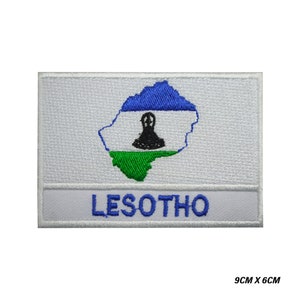Könnte beinhalten: Weißer gestickter Aufnäher mit der Umrandung von Lesotho, den Farben der Landesflagge und dem Wort "LESOTHO" in weißen Buchstaben. Der Aufnäher misst 9 cm x 6 cm.