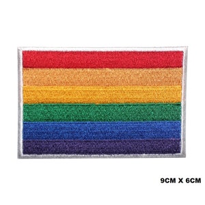 Könnte beinhalten: Ein Regenbogen-Pride-Flaggen-Patch mit sechs horizontalen Streifen in den Farben Rot, Orange, Gelb, Grün, Blau und Lila. Der Patch ist 9 cm x 6 cm groß und hat einen weißen Rand.
