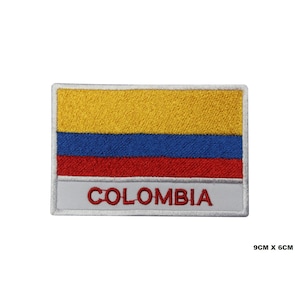 Puede incluir: Parche bordado con la bandera de Colombia con rayas amarillas, azules y rojas. El parche tiene un borde blanco y la palabra "COLOMBIA" en letras rojas.