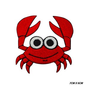 Op de afbeelding: Geborduurde rode krabpatch met grote scharen en wiebelogen. De krab heeft een lachende mond en is 7 cm x 6 cm groot. De patch staat op een witte achtergrond.