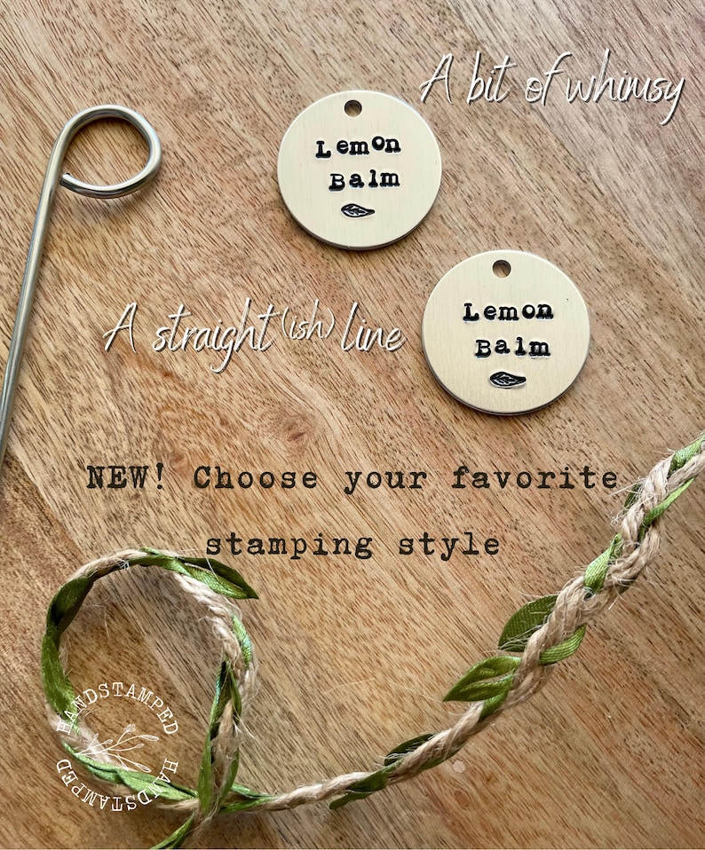 Op de afbeelding: Twee messing labels met de tekst "Lemon Balm" erop gestempeld. De labels liggen op een houten oppervlak met een groen-bruin touw met bladeren. De tekst "A bit of whimsy" en "A straight (ish) line" staat boven de labels. De tekst "NEW! Choose your favourite stamping style" staat onder de labels.