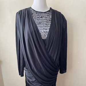 May include: A black long-sleeved dress with a draped bodice and a sequined neckline.