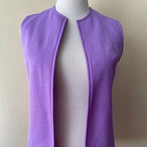 Puede incluir: Un chaleco morado sin mangas, con cuello en V y una abertura larga en la parte delantera.