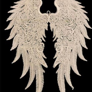 May include: A pair of white lace angel wings with intricate detailing. The wings are delicate and feminine, perfect for adding a touch of whimsy to any project.