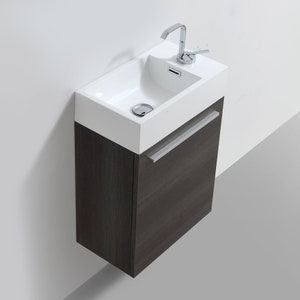 Puede incluir: Un peque&ntilde;o tocador de ba&ntilde;o rectangular blanco con un lavabo simple y un grifo cromado. El tocador tiene un gabinete de madera gris oscuro con una manija plateada.
