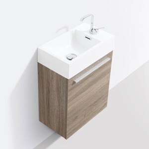 Puede incluir: Un lavabo de ba&ntilde;o de cer&aacute;mica blanca con un grifo cromado montado en un mueble de ba&ntilde;o de madera marr&oacute;n con un solo caj&oacute;n y una manija plateada.