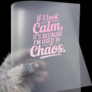 May include: A translucent, frosted sheet featuring the pink text "IF I LOOK Calm, IT'S BECAUSE I'M USED TO THE CHAOS." The lettering is arranged in a multi-line, stylized font layout centered on the surface of the semi-transparent material.