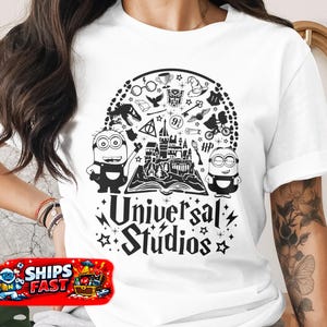 May include: White t-shirt featuring a black graphic design with Minions, Hogwarts castle, and various Harry Potter-themed icons. The text "Universal Studios" is displayed below the central design, surrounded by stars.