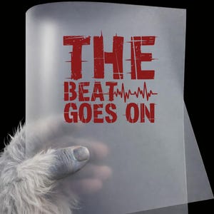 May include: A translucent sheet with the red text "THE BEAT GOES ON" and a heartbeat graphic. The sheet is held by a hand with light gray fur and a gray finger. The background is black.