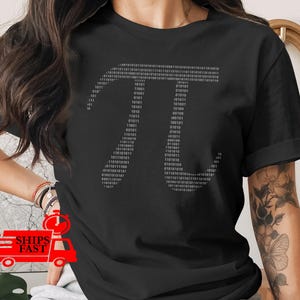 May include: Black t-shirt featuring a gray binary code design in the shape of the mathematical symbol Pi. The design is made up of a series of 1s and 0s. A casual, comfortable tee for math enthusiasts.