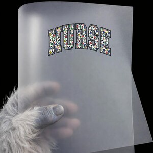 May include: A translucent sheet of paper with the word "NURSE" printed in a collegiate font. The letters are filled with a colorful floral pattern. The paper is held by a hand with blue skin and white fur.