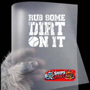 May include: A translucent sheet with the text "RUB SOME DIRT ON IT" in white, along with a baseball graphic. A red sticker with the words "SHIPS FAST" and a cartoon graphic is visible.