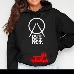 May include: Black hoodie with a white graphic of a circle and drumsticks, with the text "DUT. DUT. DUT." below. A red graphic of a truck with the words "SHIPS FAST" is on the front pocket.