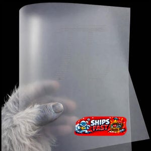 May include: A translucent sheet of paper with a large "T" formed by small dots. A red sticker with the words "SHIPS FAST" and a cartoon image of a snowman and treasure chest is affixed to the paper.