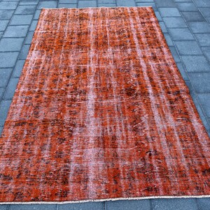 May include: A vintage-style rug with a faded orange and brown color scheme. The rug has a distressed look with a subtle pattern.
