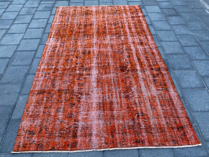 May include: A vintage-style rug with a faded orange and brown color scheme. The rug has a distressed look with a subtle pattern.