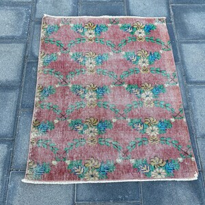May include: A vintage floral patterned rug with a red background and green vines. The rug has a white fringe border.