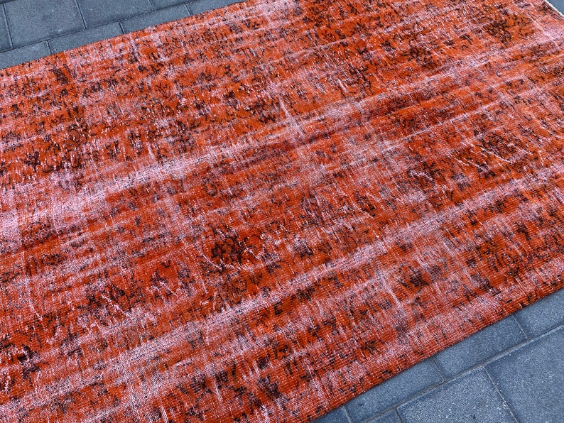 May include: A distressed rug with a faded orange and black pattern. The rug has a worn and vintage look.