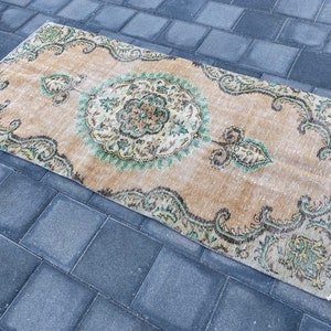 May include: A vintage style rug with a beige background and a green and brown floral pattern. The rug has a distressed look and is perfect for adding a touch of bohemian style to any room.