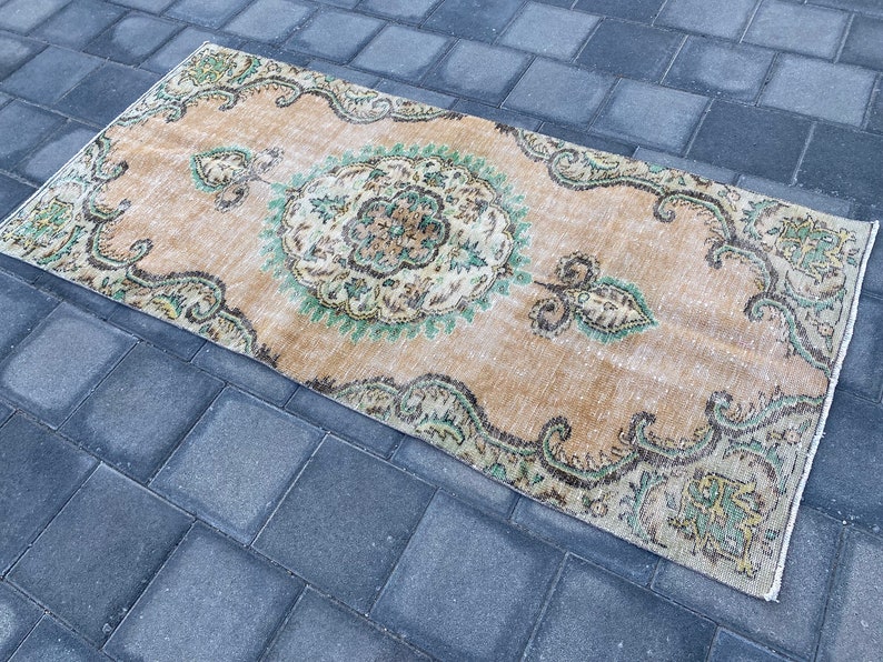 May include: A vintage style rug with a beige background and a green and brown floral pattern. The rug has a distressed look and is perfect for adding a touch of bohemian style to any room.