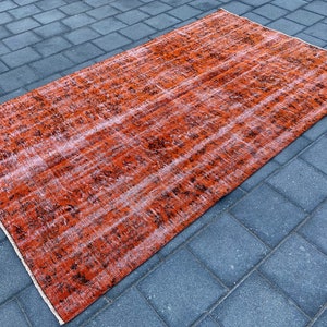 May include: A vintage-style rug with a faded orange and black pattern. The rug has a distressed look and is made of a soft, woven material.