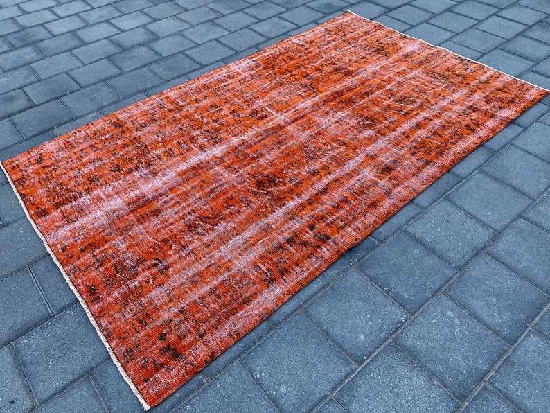 May include: A vintage-style rug with a faded orange and black pattern. The rug has a distressed look and is made of a soft, woven material.