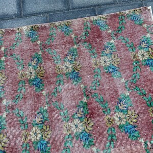 May include: A vintage rug with a floral pattern in shades of pink, green, yellow, and blue. The rug has a distressed look and is made of a woven material.